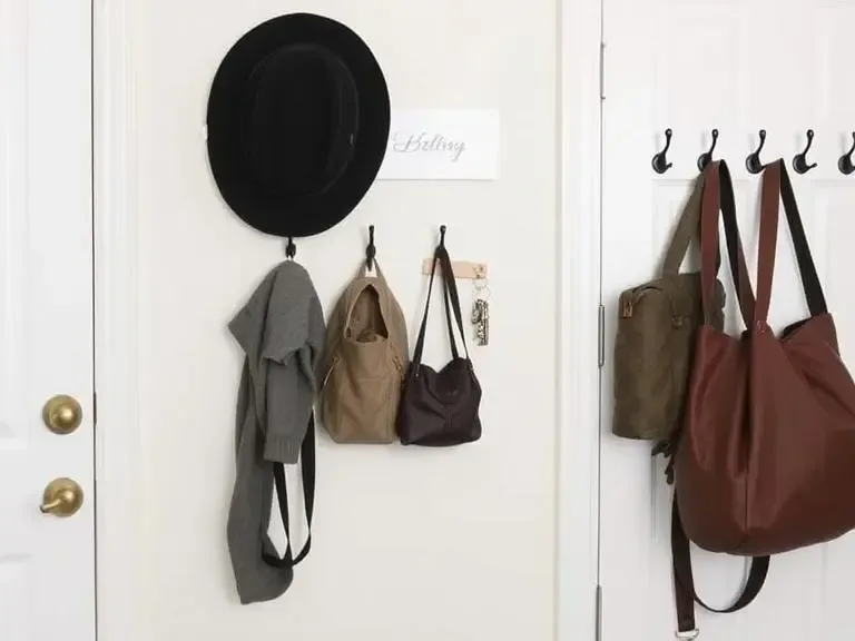 Entryway wall with command hooks holding bags, hats, and keys neatly organized.