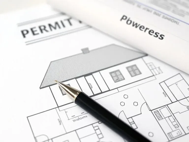 Building permit paperwork and a construction plan on a desk.