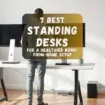 Modern home office setup featuring a person using a stylish standing desk with dual monitors, natural light, and minimalist decor.